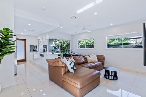 Open-plan living space with a large tan leather sectional and a smart TV.