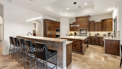 Spacious gourmet kitchen with wood cabinetry, modern lighting & large island!