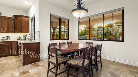 Cozy dining with rustic table, elegant lighting & lush backyard views!