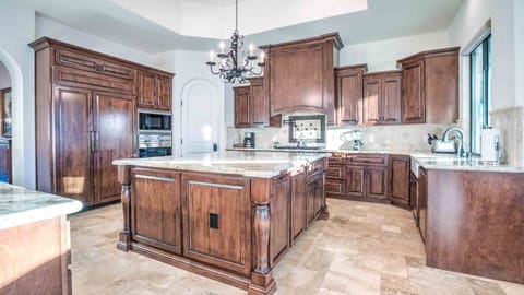 Gourmet kitchen with rich wood cabinetry, granite counters, and a large island.