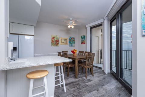 Gather around the wooden dining table, surrounded by colorful artwork and enjoying refreshing breezes from the balcony