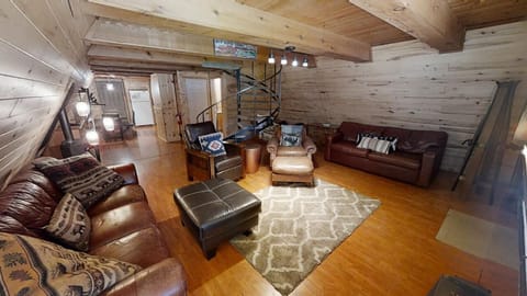 Relax in this warm, cabin-style living room with leather sofas, cozy seating, and charming wood-paneled walls under rustic beams—your perfect mountain getaway retreat.