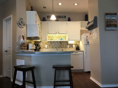 Newly updated kitchen with glass backsplash and under cabinet lighting.