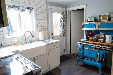 An antique Royal Charter Oak stove now serves as a charming coffee and tea bar complete with frother, sugar and creamer