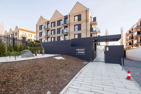 A view of the modern apartment complex, showcasing contemporary architecture with brick and glass facades, surrounded by landscaped paths and greenery.