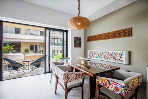 Your bright dining area blends natural wood and vibrant handcrafted textiles, with glass doors opening to your private balcony and inviting tropical views.