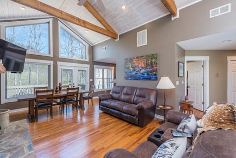 Living room with vaulted ceilings, floor-to-ceiling windows, wood-burning fireplace, and Smart TV (streaming & cable available).