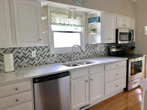 Stunning Sun House kitchen with quartz countertops and stainless appliance.