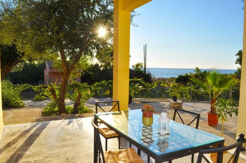 Large covered terrace with garden furniture and a view of the sea.