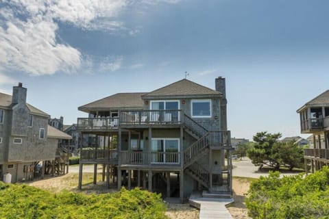 A charming coastal retreat with elevated decks and coastal-style architecture, situated in a peaceful beachside neighborhood with natural dune landscaping.
