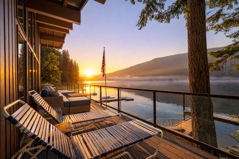 Lakeside deck with comfortable seating overlooking pristine mountain lake at sunrise.
