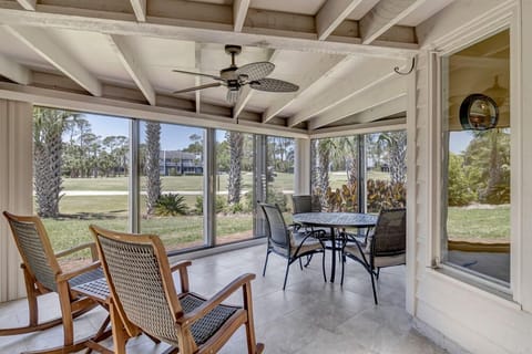 - Enjoy serene mornings or sunset dinners on this screened patio overlooking palms and greenery
- Rocking chairs and a ceiling fan create a breezy space for coffee or cards
- Spacious layout blends comfort and nature for all season relaxation