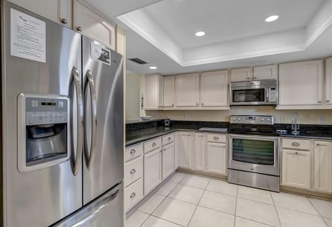 - Stay fully stocked with this spacious stainless steel fridge beside modern appliances and deep counters
- Neutral tones and tile flooring add warmth to this practical layout
- Open design makes cooking and snacking easy for any group size