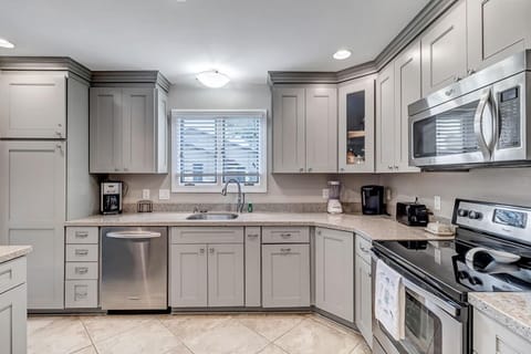 - Fully stocked kitchen with dishwasher, microwave, blender, and coffee station essentials
- Stylish counter space and corner sink setup make meal prep simple and efficient
- Modern stainless steel finishes complement warm, tiled flooring throughout