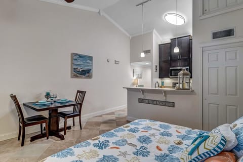 - Full view of living, dining, and kitchen areas with coastal art and neutral tones
- Compact table for two pairs perfectly with island bar for multiple dining spots
- Elevated ceilings and clever layout make this studio style setup feel surprisingly spacious