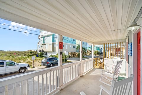 Relax on your covered porch with rocking chairs, enjoying views of colorful beach houses and natural dunes.