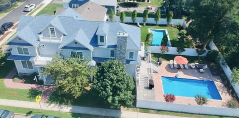 Drone view of the house, showing the yard with the porch, paver patio, and pool.