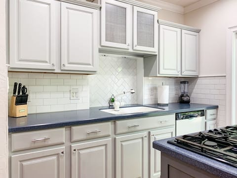 Bright and open kitchen with abundant counter space, cooking tools, dishwater and appliances.