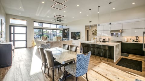 Dining space with chic furnishings, recessed lighting & kitchen backdrop.

