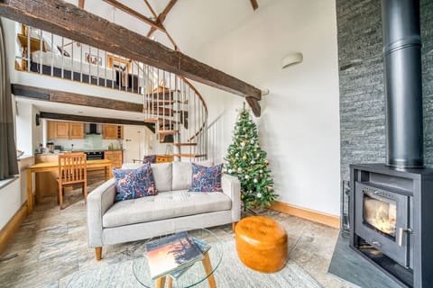 Double height barn living with mezzanine, log burner and spiral stair.