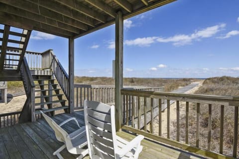 The property sits among coastal dunes and natural vegetation, offering a peaceful retreat with views of the surrounding beach landscape and pathways leading to the shore.