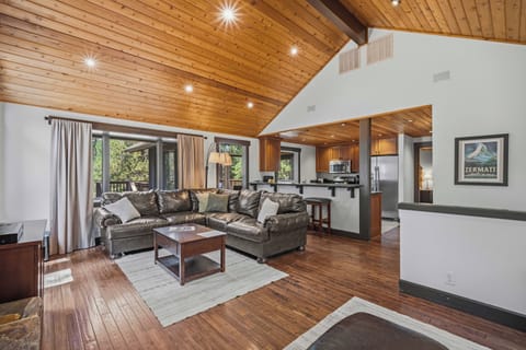 Mountain retreat with soaring vaulted wood ceilings, expansive windows, and forested views. Plush leather sectional, open layout, and fully-equipped kitchen make it perfect for après-ski relaxation.