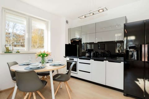 A kitchenette with a black and white color scheme, featuring modern appliances and a sleek look.