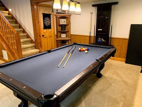A spacious game room with a pool table, dartboard, and warm lighting creates the perfect setting for family fun and group entertainment during your stay.