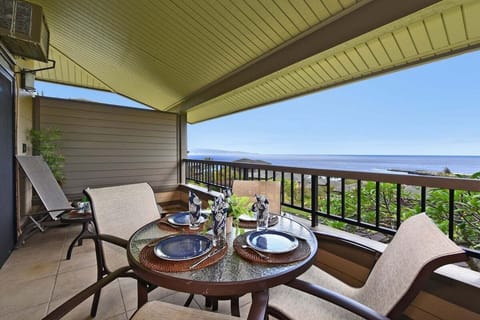 Ocean-view lanai with a four-seat dining table and ceiling fan, ideal for relaxing meals overlooking lush Kapalua scenery.