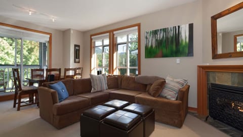 - Warm living room with cozy fireplace and plush sectional seating  
- Bright windows bring in forest views and natural Whistler light  
- Ideal for relaxing movie nights or après-ski gatherings  
