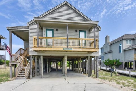 Classic coastal architecture on stilts provides elevated living and covered parking, with a welcoming front porch overlooking the beach neighborhood.