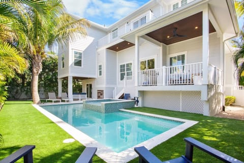 Stunning white tropical home with private pool surrounded by lush palm trees and manicured lawn in a serene setting.