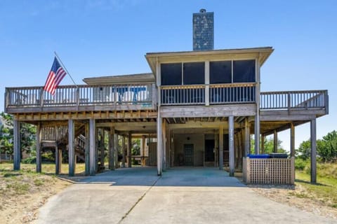 A classic coastal retreat elevated on sturdy pilings with wraparound decks and covered parking below. The design offers protection from coastal weather while providing multiple outdoor spaces to enjoy the sea breeze.