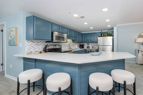 Gather around the stylish bar seating in the kitchen, featuring sleek countertops and vibrant blue cabinetry