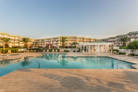 Pool area with outdoor tables, chairs, loungers, and table umbrellas