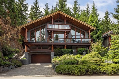 - Chalet exterior surrounded by lush greenery and tall pine trees  
- Large windows and wooden architecture create timeless mountain charm  
- Peaceful alpine escape blending nature with modern comfort  