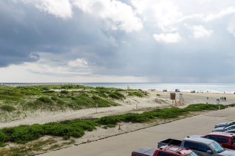 Expansive beachfront stretches along the coastline with convenient parking and natural dune vegetation framing the sandy shores.