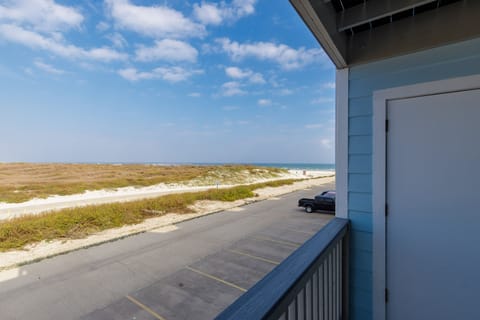 Coastal views stretch across dunes and beach from your private balcony, with convenient parking below and endless ocean horizons ahead.
