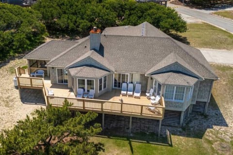Coastal retreat featuring spacious wraparound decks, mature oak trees, and beachfront access, nestled in a quiet residential neighborhood.