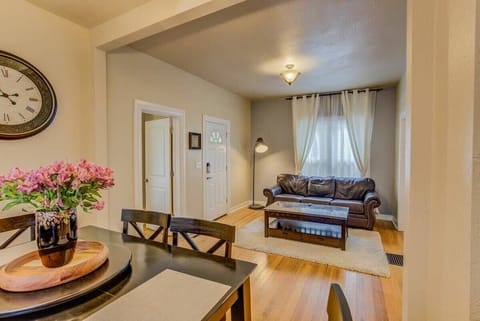 Warm, open living space with hardwood floors and comfy seating—stretch out after a day out, then gather at the dining table with fresh blooms nearby.