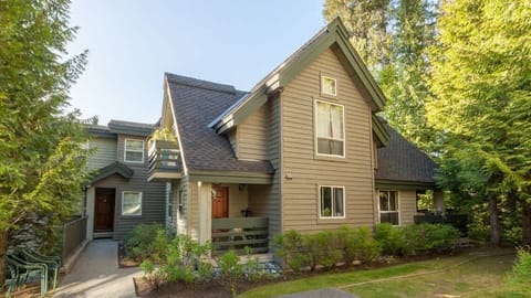 - Summer view of the cozy mountain townhouse  
- Surrounded by tall trees and peaceful trails  
- Perfect base for year-round Whistler fun  
