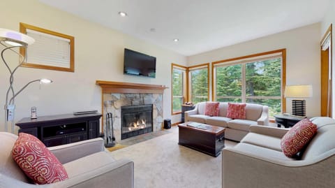- Bright living space with large windows framing lush forest views  
- Cozy fireplace and stylish decor for relaxing après-ski moments  
- Ideal Whistler retreat combining comfort, style, and mountain scenery  