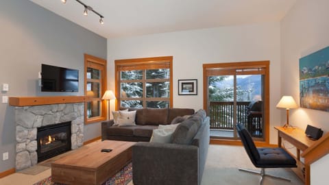 - Living room with stone fireplace and mountain views through windows  
- Plush seating and warm lighting create a relaxing mountain vibe  
- Step onto the balcony and enjoy snowy forest scenery  
