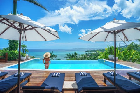 A guest enjoys the infinity pool and ocean view as seen from the veranda
