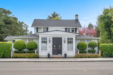 Charming white colonial home with manicured landscaping and welcoming front entrance in a peaceful residential setting.
