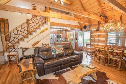 Great Room with Wood Floors, Exposed Beams, and Custom Branch Balustrade on Stairway to Upstairs Suite
