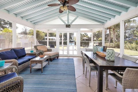 Screened sunroom with blue ceiling, wicker furniture, dining table