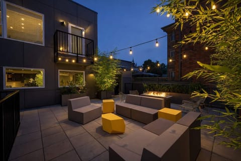 Modern outdoor lounge with cozy seating, string lights, and lush greenery—perfect for evening relaxation and social gatherings.
