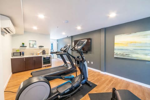 Well-equipped fitness room with cardio machines, free weights, and bright modern space to keep up your workout routine.
