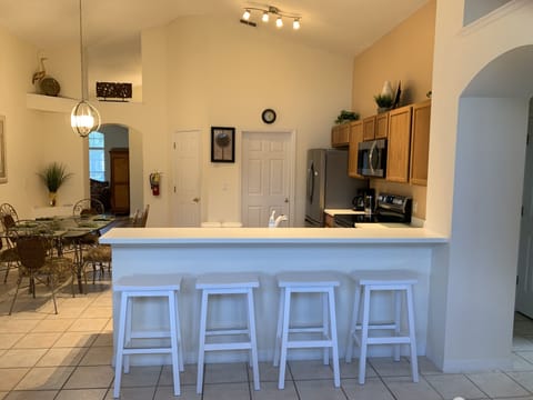 Kitchen view from family room with bar stools and kitchen table 